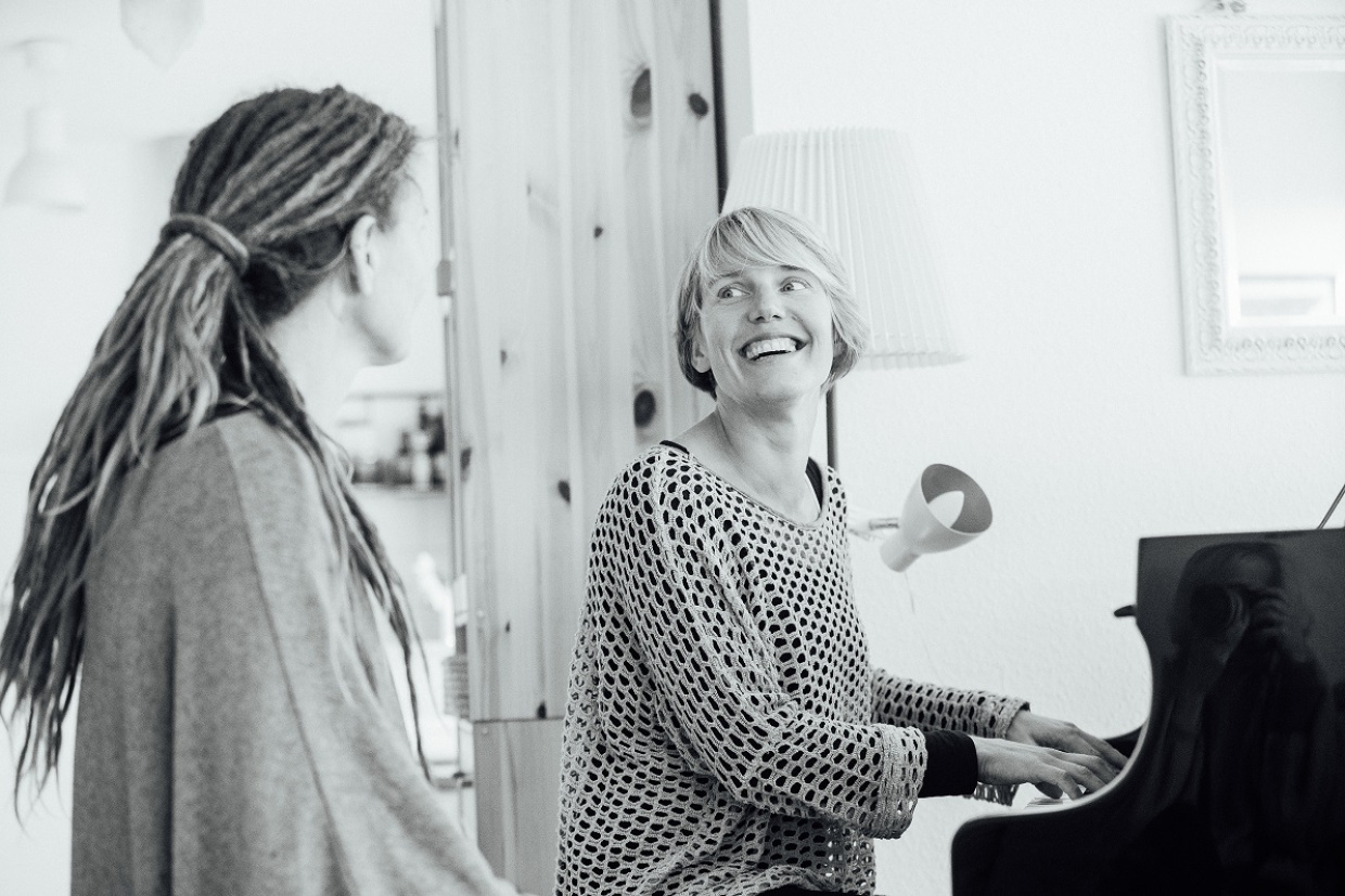 Zwei Frauen machen Musik, eine sitzt am Klavier