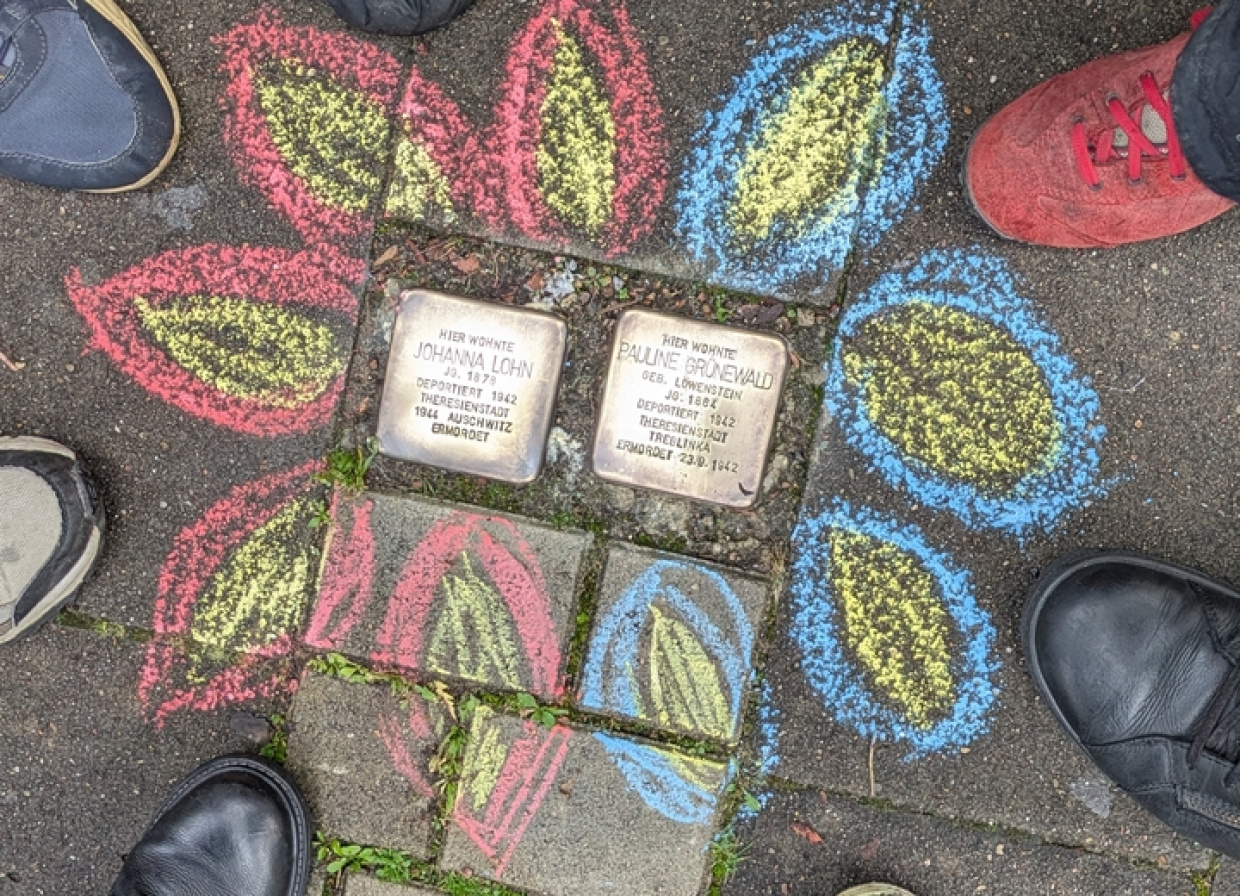 Mit Straßenmalkreide verzierte Stolpersteine auf dem Gehweg