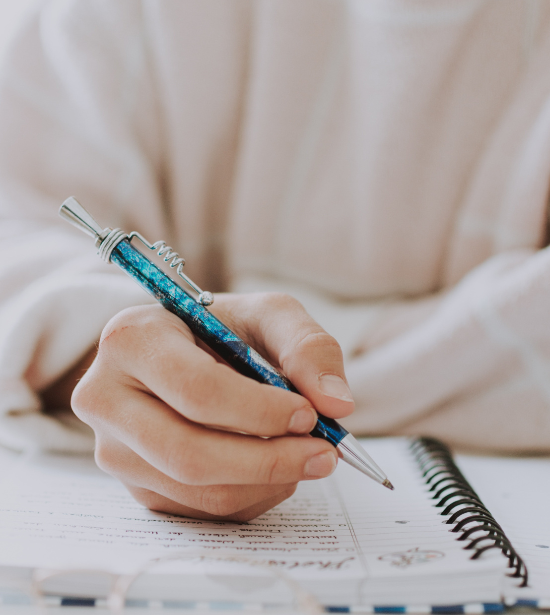 Eine Person schreibt mit einem Stift auf ein Blatt Papier