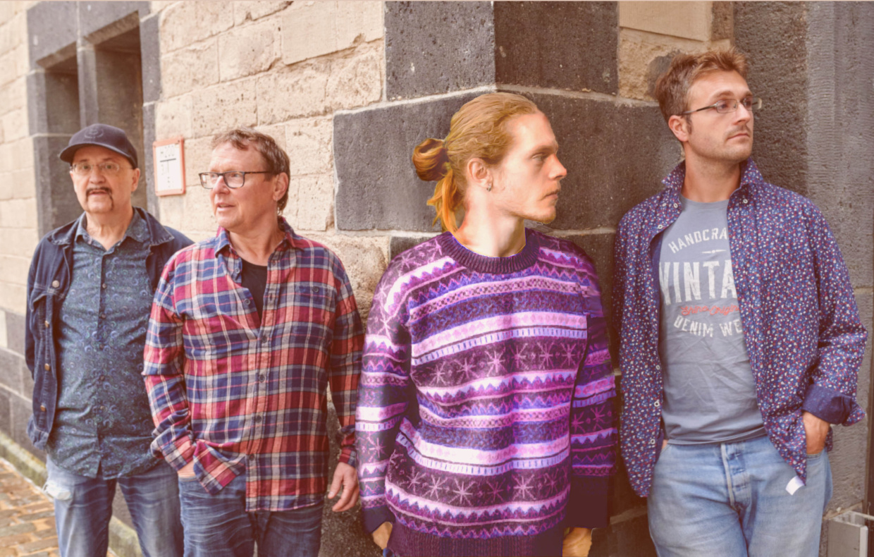 Vier Männer bunt gekleidet stehen vor einer Wand