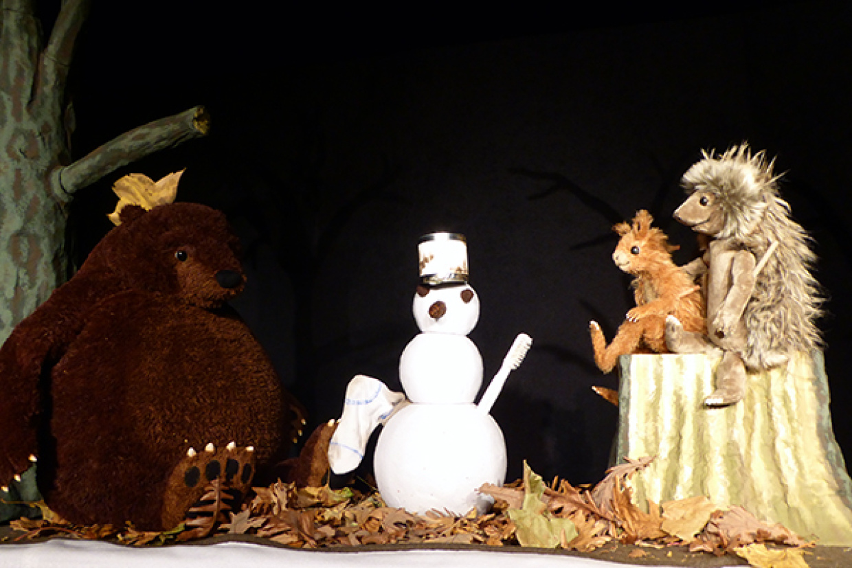 Eichhorn, Bär und Igel sitzen vor einem Schneemann