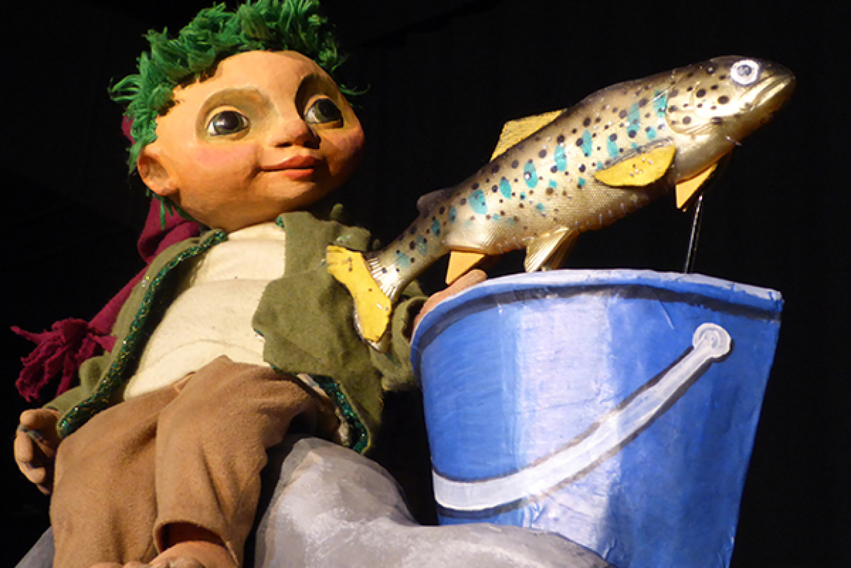 Der kleine Wassermann schaut sich einen Fisch an