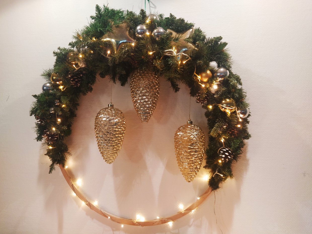 Ein Adventskranz an der Wand mit goldenen Tannenzapfen