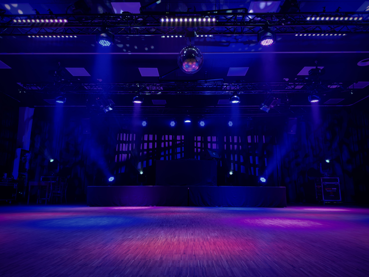 Das Bild zeit eine bunt beleuchtete Tanzfläche und Bühne.