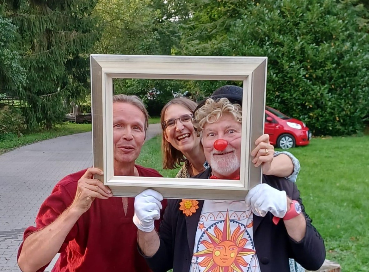 Oda Bobbert, Vincent und Clown Theo lachen durch einen leeren Bilderrahmen.