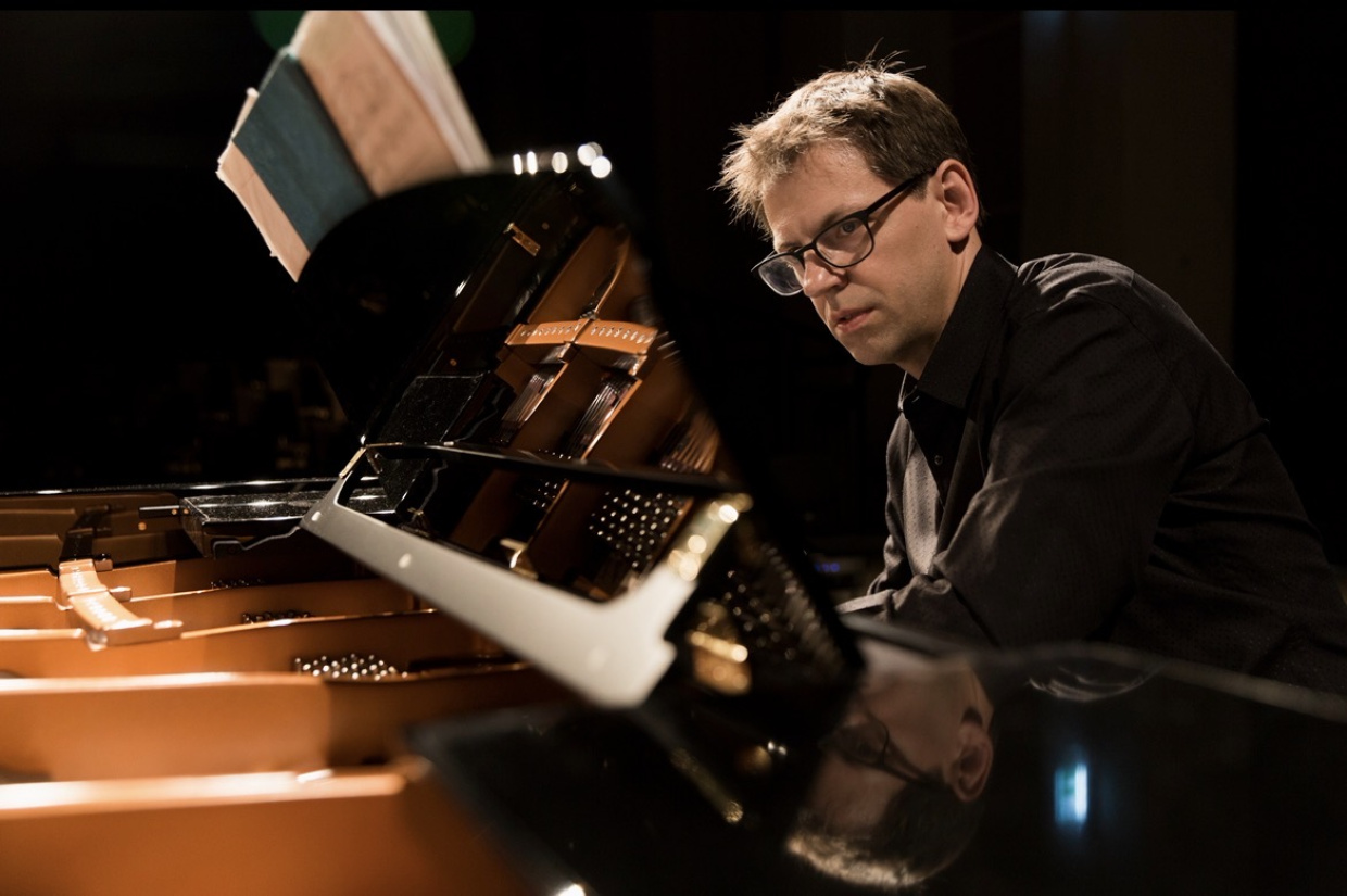 Der Pianist Florian Hölscher sitzt am Flügel und spielt aus einer Partitur. 