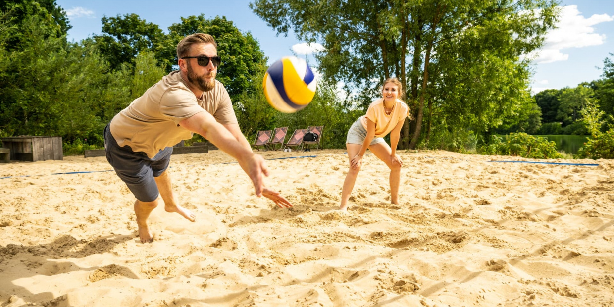 Zwei Personen spielen Beachvolleyball 