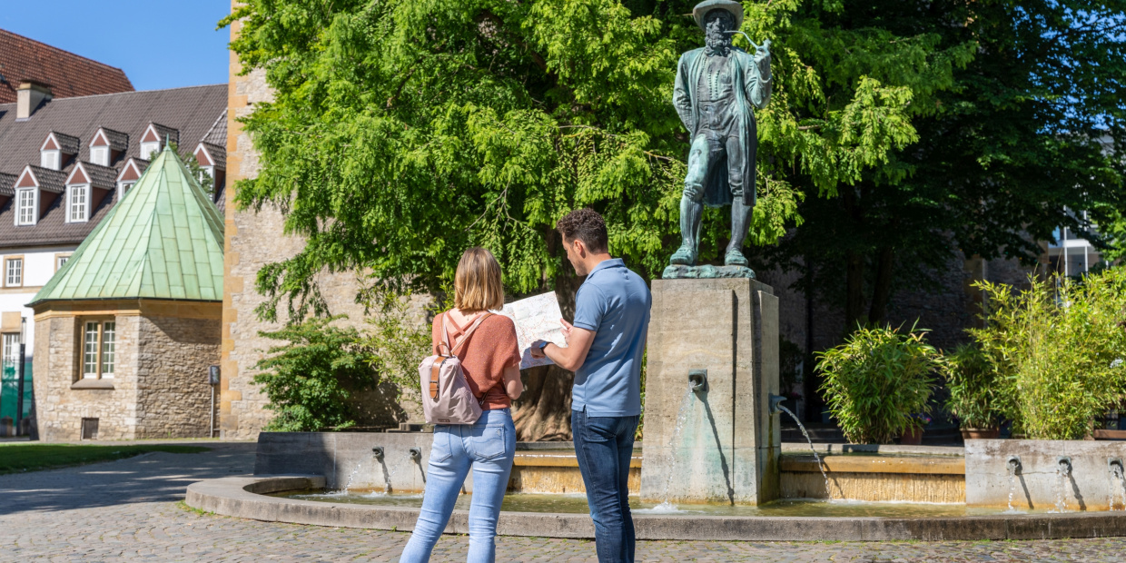 © Teutoburger Wald Tourismus | P. Gawandtka Mann und Frau stehen vor dem Leineweber-Denkmal