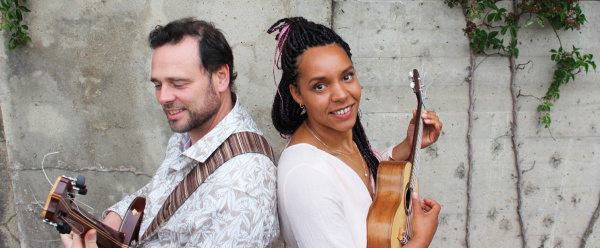 Ein Mann und eine Frau stehen Rücken an Rücken mit ihren Gitarren