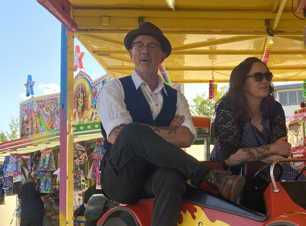 Musikerduo aus Mann und Frau sitzen auf einem Pferdekarussell