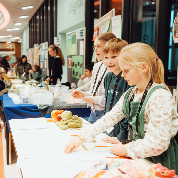 Zu sehen sind einige Kinder, die ihre Forschungsergebnisse bei Jugend forscht an ihrem Stand präsentieren