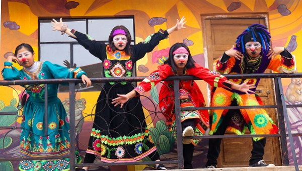 Bunt gekleidete Kinder springen vor einer Fassade herum