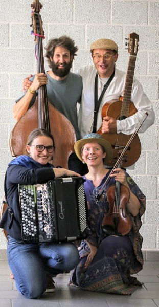 Vier MusikerInnen sitzen und stehen mit ihren Instrumenten