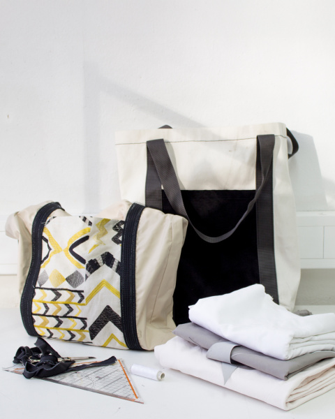 Zwei genähte Taschen vor weißem Hintergrund. Im Vordergund liegen diverse Nähutensilien.