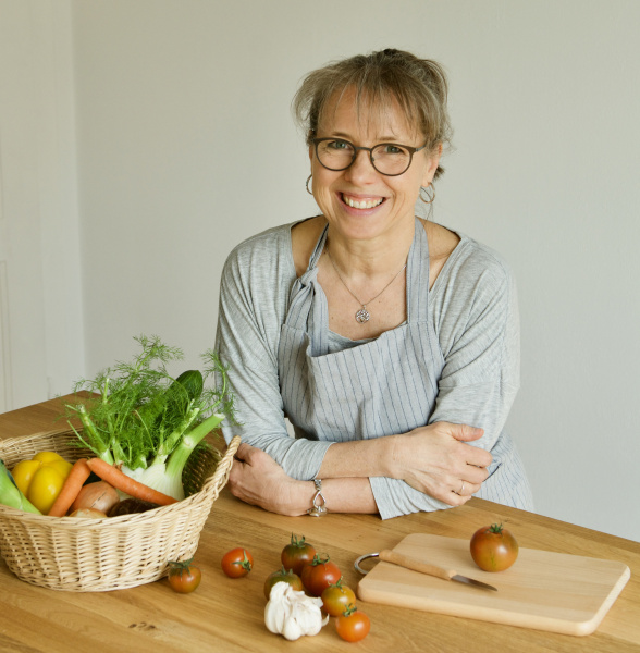 Foto der Kursleiterin in ihrer Lehrküche mit einem Korb Gemüse