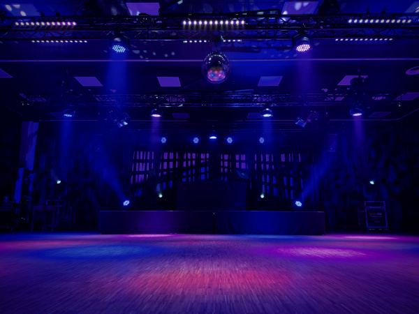 Das Bild zeigt eine Bunt beleuchtete Bühne und Tanzfläche.