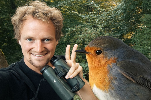 Rotkehlchen im Vordergrund und Referent mit Fernglas im Hintergrund