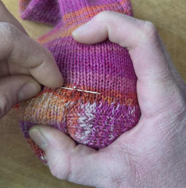 Das Bild zeigt die Reparatur einer Wollsocke.