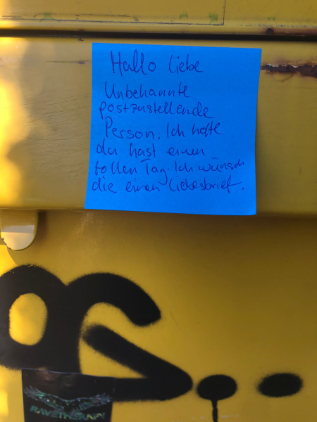 eine Botschaft auf einem blauen Post-It klebt auf einem Briefkasten
