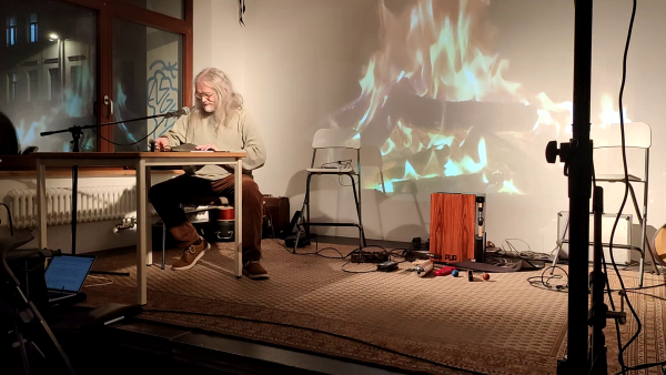Der Autor lachend auf der Bühne mit künstlichem Lagerfeuer
