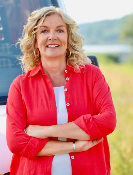 Portraitfoto der Autorin in roter Bluse mit verschränkten Armen vor ihrem Camper