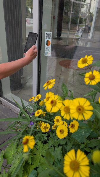 Eine Person scannt mit einem Smartphone den QR-Code einer Station der SDG-Stadtrallye.