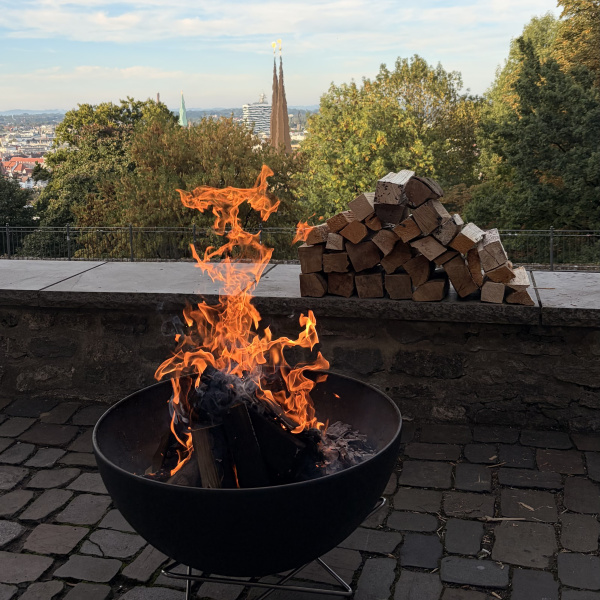 Feuerschale mit brennendem Holz vor Bielefelder Stadtpanorama