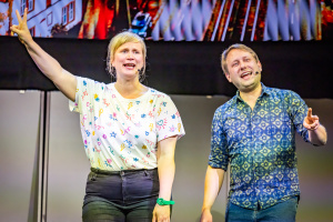 Zwei Personen auf einer Bühne während einer Präsentation oder Auftritt.