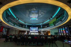 Großer Saal mit Publikum, Bühne und beleuchteter Decke.